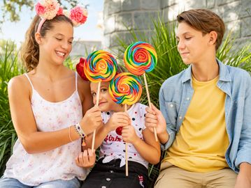 Three kids holding colorful lollipops and smiling.