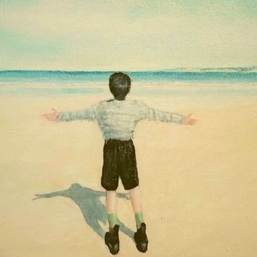 Child facing the sea with arms wide open.