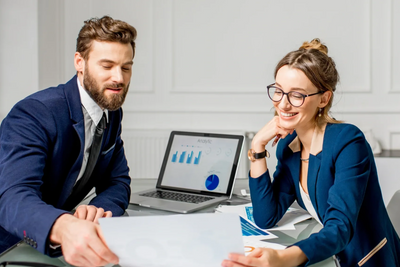 Two colleagues discussing documents and data charts in a modern office.