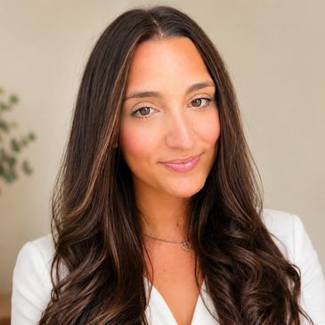 Woman with long brown hair wearing a white top.