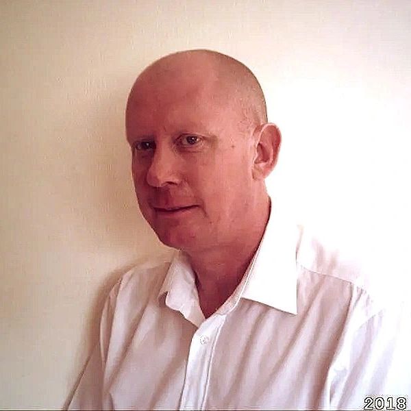 Portrait of a bald man in a white shirt against a plain background.