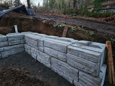 Concrete retaining wall blocks partially installed on a construction site.