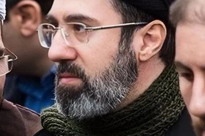 Bearded man wearing glasses and green scarf in close-up.