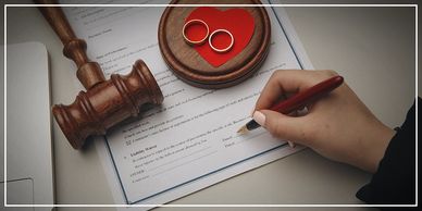 Person signing a document beside a gavel and two rings.