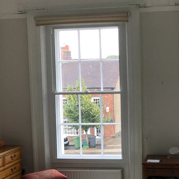 View through a window showing a street with greenery and buildings.