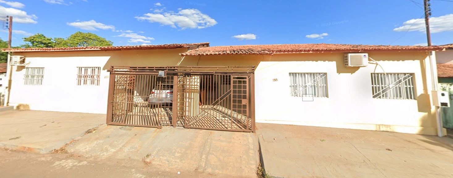 Fachada de casa branca com portão de ferro e garagem.