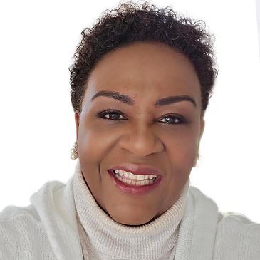 Smiling woman with curly hair wearing a white turtleneck sweater.