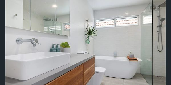 Bathroom renovation with bath, glassed shower and bathroom vanity unit with stone custom countertop