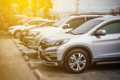 Row of parked silver cars with sunlight.