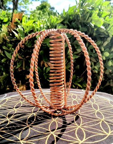 Intricate copper wire sculpture with twisted rings and coils on patterned fabric.
