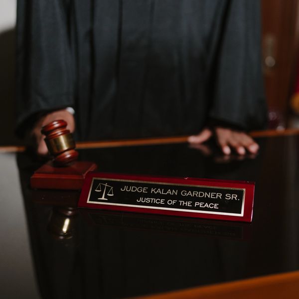 Judge Kalan Gardner Sr. standing behind a desk with a nameplate and gavel.