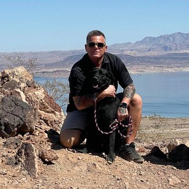 Veteran with his service dog posing at a lake.