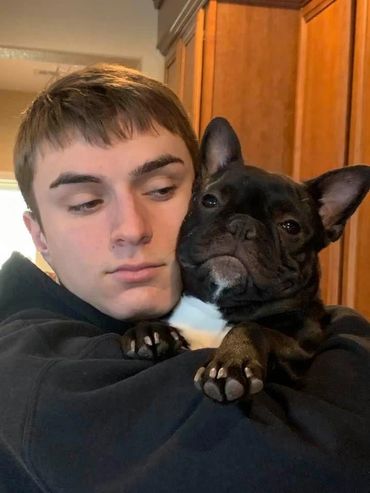 A young man holding Melly the French Bulldog.