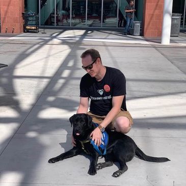 A male student working with his young dog in training to be an animal assisted therapy dog.
