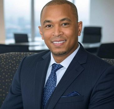 Professional man in a navy suit smiling confidently in an office setting.