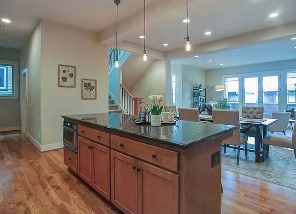 Open-concept room with hardwood floors and a kitchen island with black granite countertops.