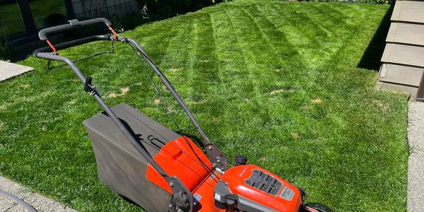 Red lawn mower on a freshly mowed green lawn.