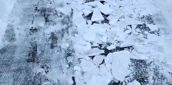 Snow and ice chunks scattered on a cleared road surface.
