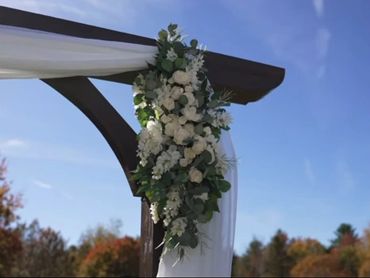 Classic white wood flower arbor with soft greenery for an elegant wedding ceremony