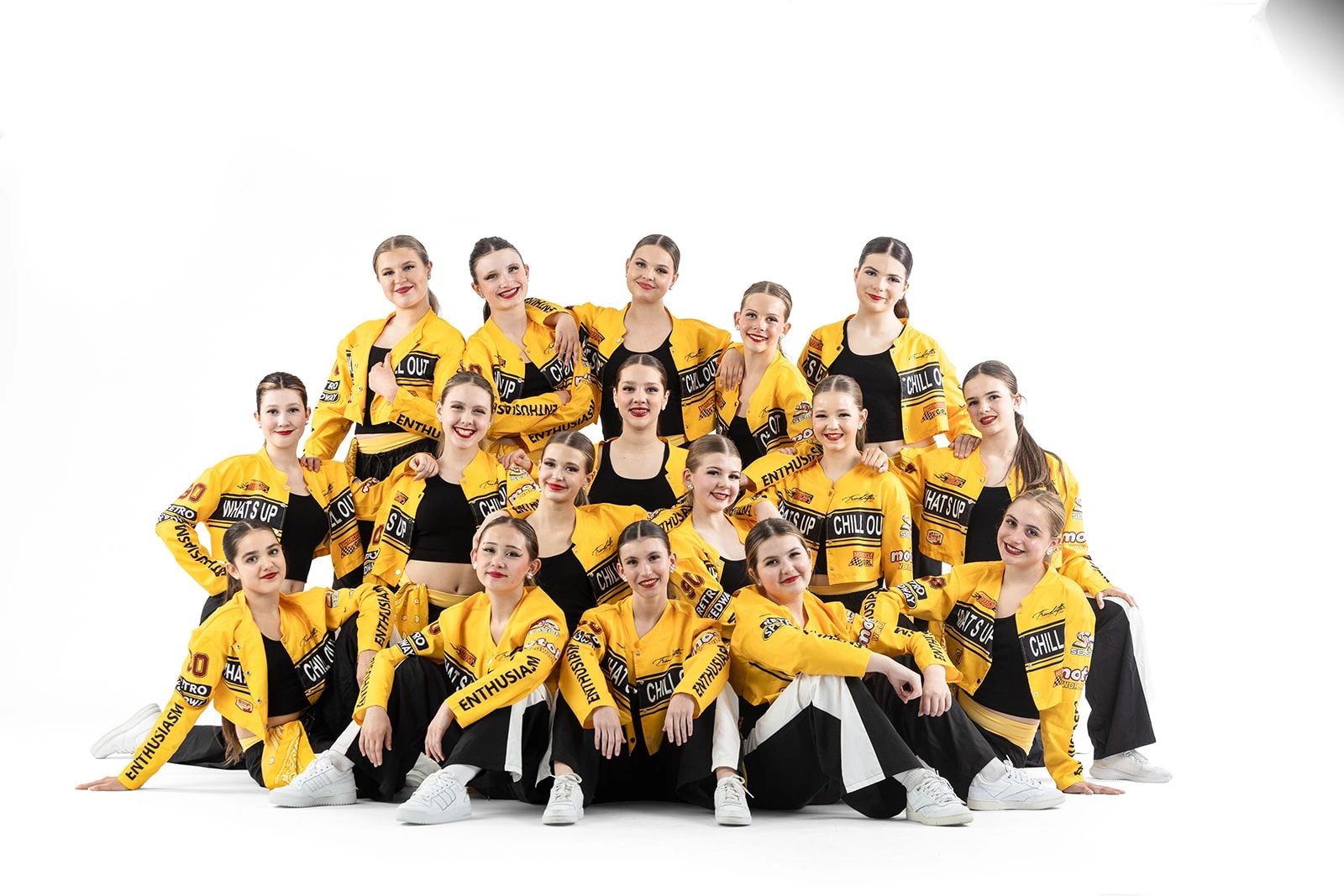 Group of young dancers in yellow jackets posing together.