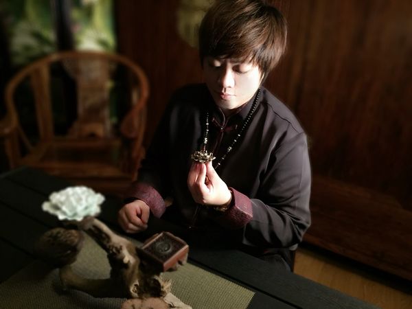 Person examining an ornate object in a dimly lit cozy room.