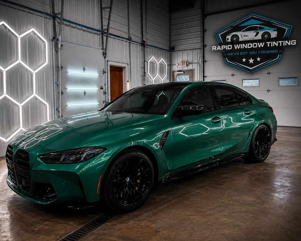 Green BMW sedan inside a garage with neon lights.