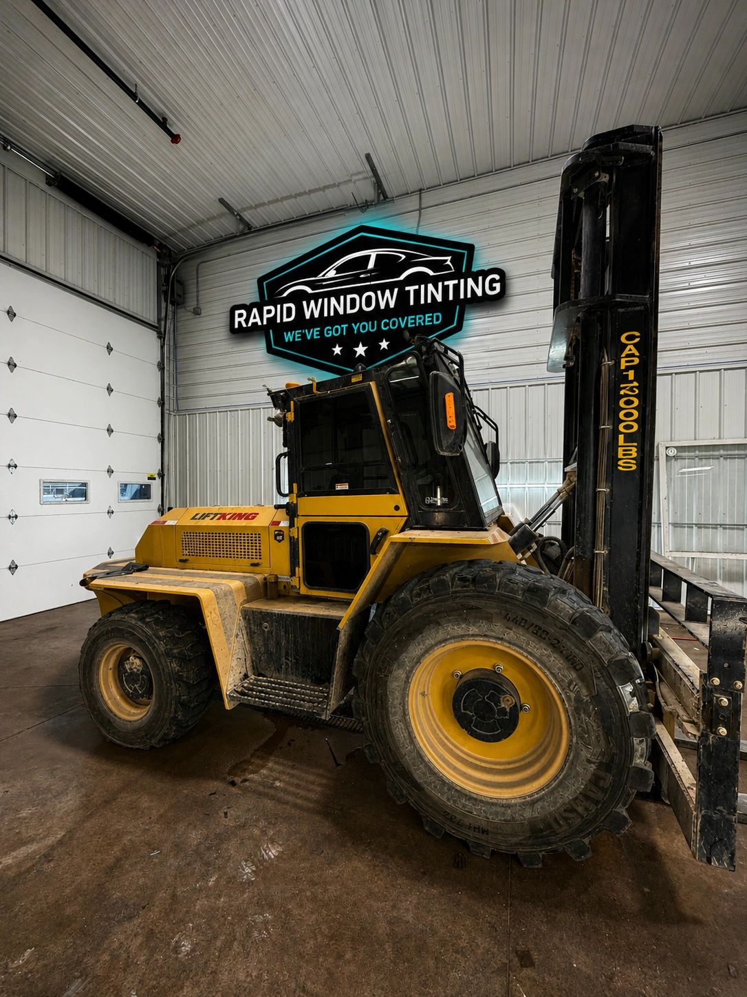 Yellow forklift inside a garage with a Rapid Window Tinting sign.