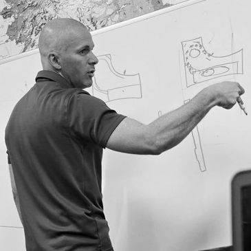 Man explaining technical drawings on a whiteboard.