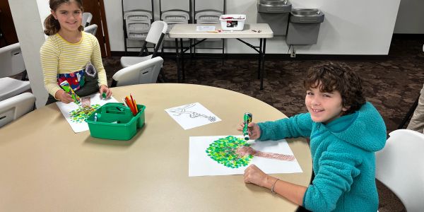Two children drawing and coloring at a table.