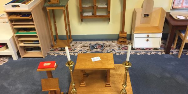 A wooden altar setup with candles and a religious book.