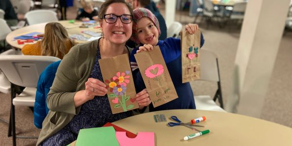 Woman and child showing decorated paper bags.