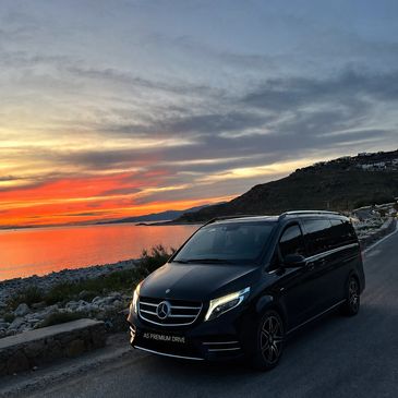 Black Mercedes van parked by the seaside at sunset.