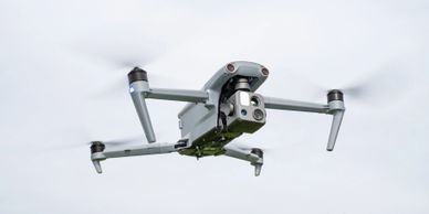 A grey quadcopter drone flying with its camera facing forward.