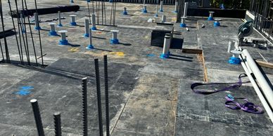 Construction site with rebar and plumbing pipes under clear blue sky.