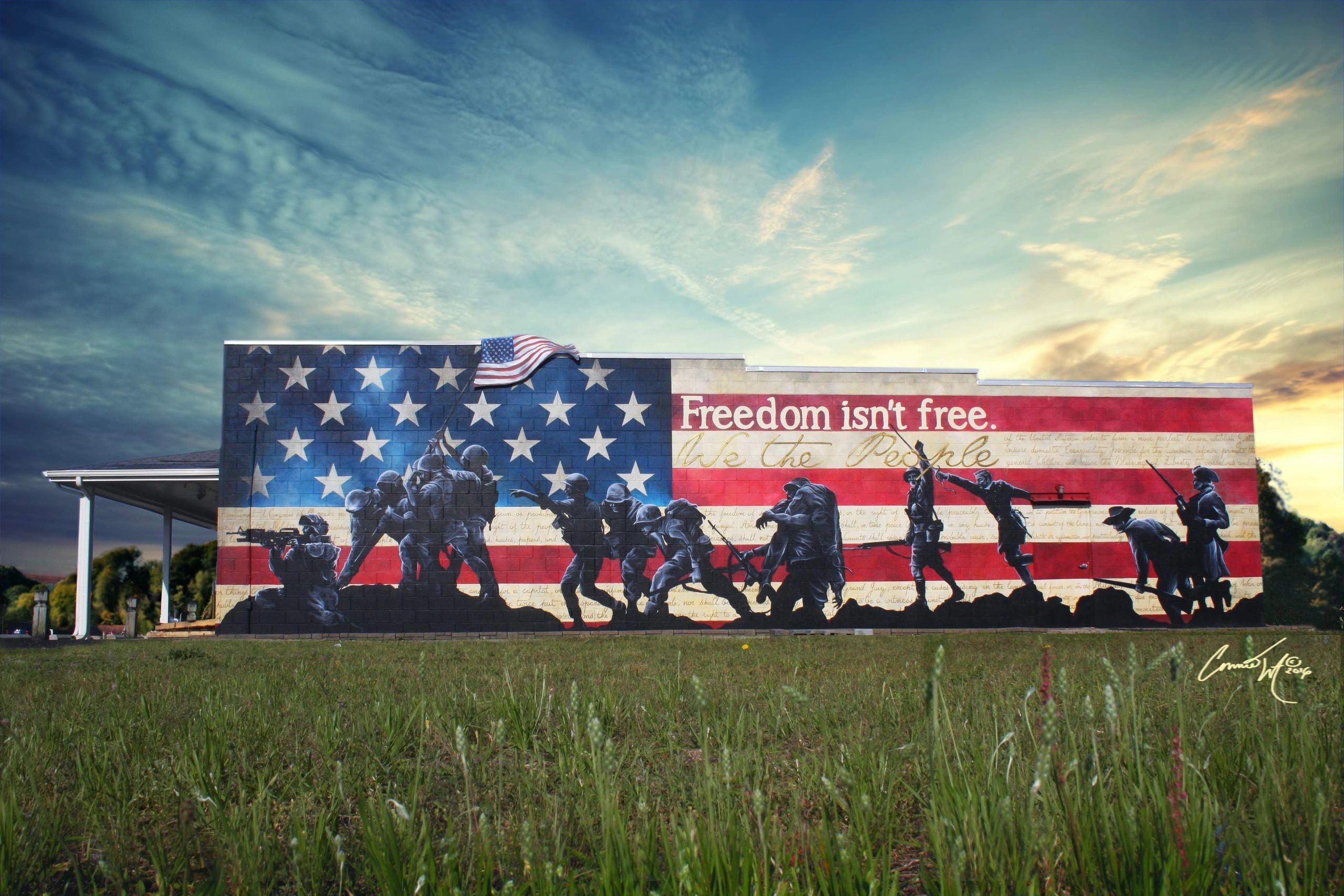 Mural on outside wall of large gun shop of flag behind silhouettes of soldiers throughout history.