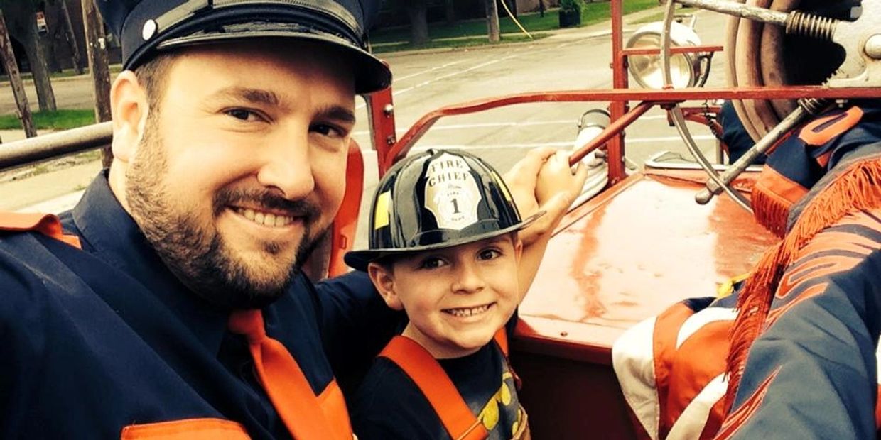 Smiling firefighter and child in a fire truck.