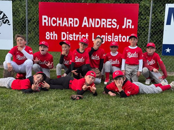 Youth baseball team posing in front of a campaign sign.
