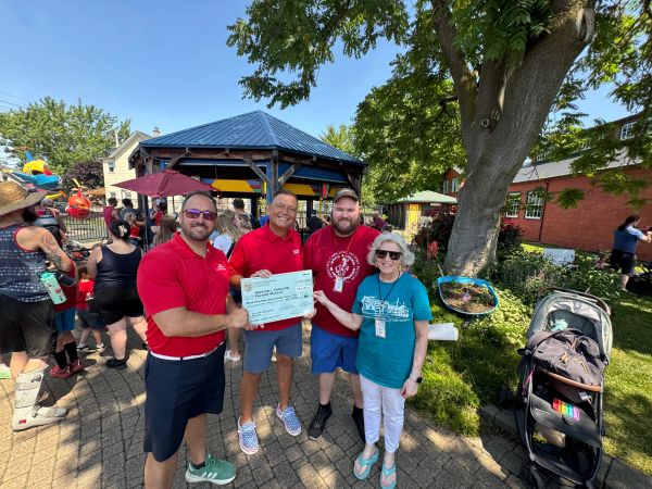 Four people holding a check at an outdoor event.