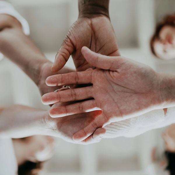 Multiple hands stacked together in unity.