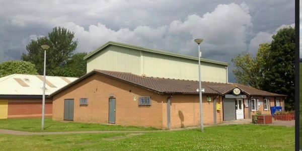 A community building with cloudy skies and green grass.