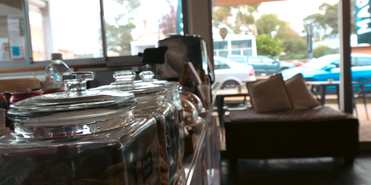 Glass jars with snacks on a counter in a cozy cafe.
