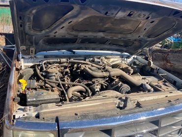 Old car engine bay with dusty components and open hood.