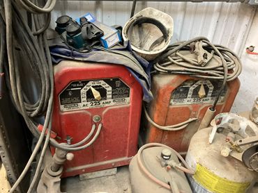 Two dusty Lincoln AC 225 amp arc welders with tools and cables.