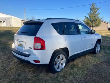 White Jeep Compass parked on grass with Iowa license plate.