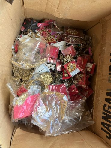 A box filled with assorted gold and pearl decorative accessories in plastic packaging.