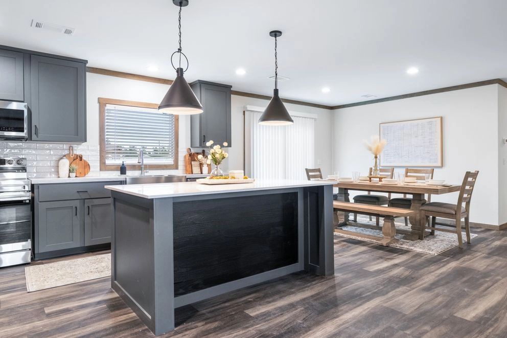 Modern kitchen with gray cabinets, island, and wooden dining set in open space.