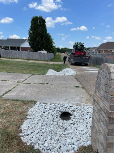 Drainage pipe surrounded by white rocks to repair a culvert