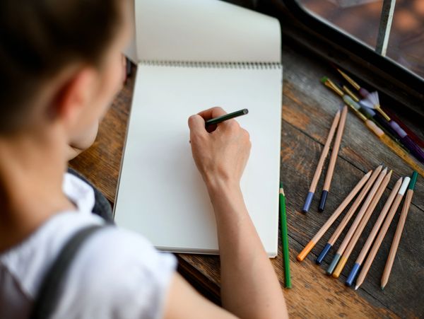 An artist drawing with pencils on paper
