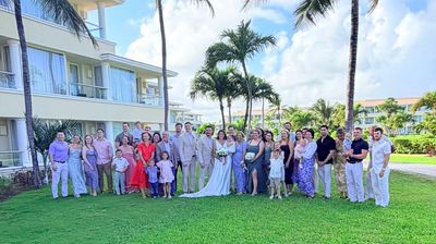 Large wedding party posing outdoors in front of a hotel.