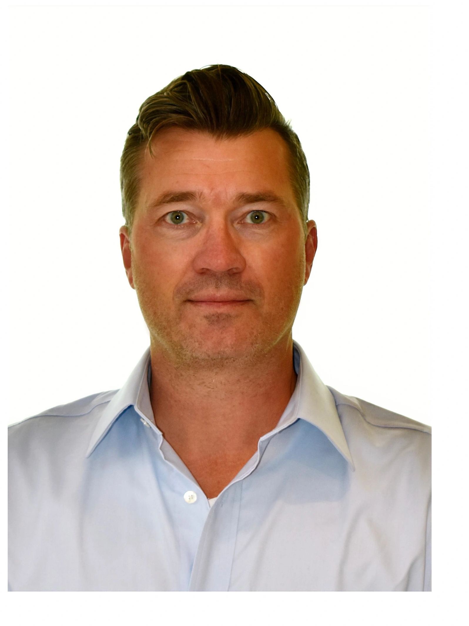 Portrait of a man with light brown hair and green eyes wearing a light blue shirt.